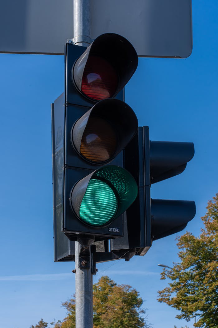 A close-up of a traffic light showing a green signal under a clear blue sky.