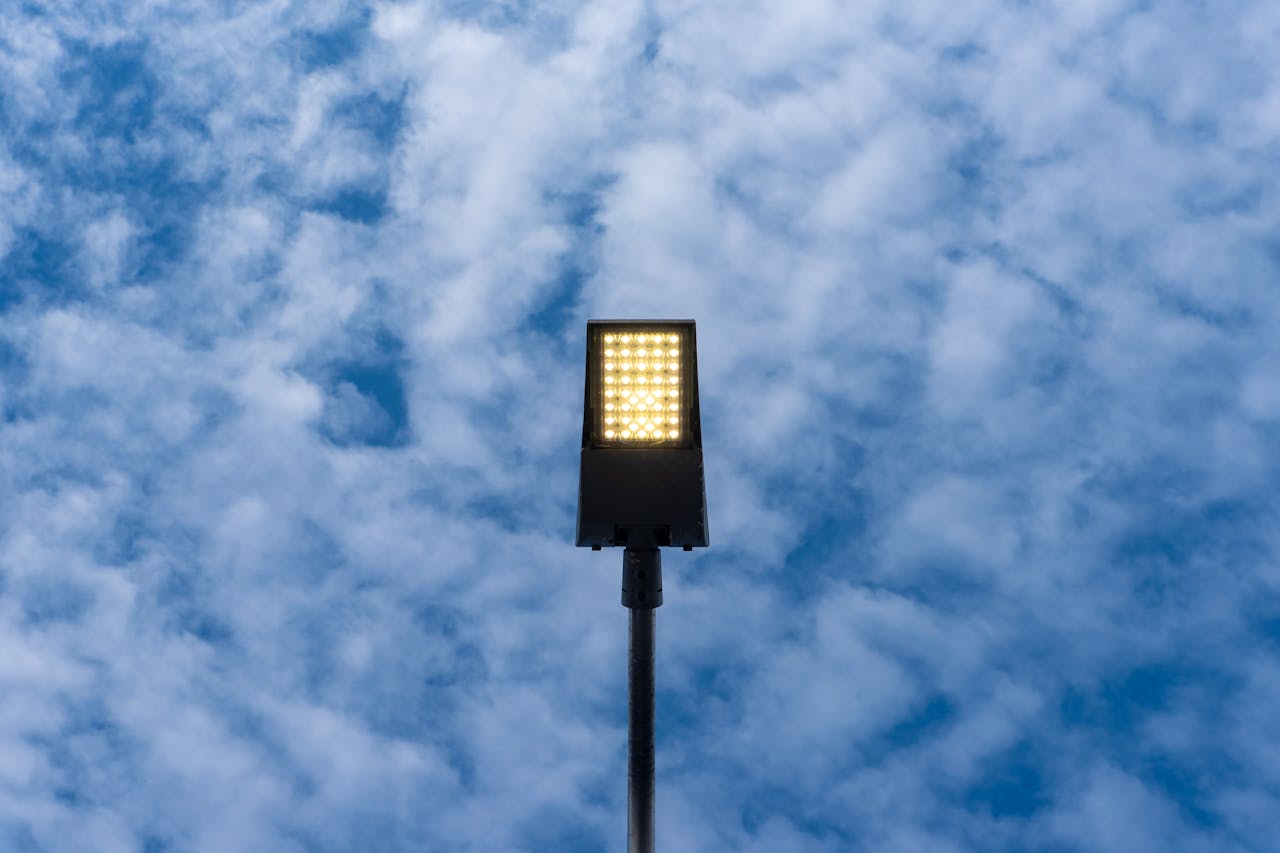 A bright LED street lamp set against a backdrop of blue sky with clouds, creating a contrast.